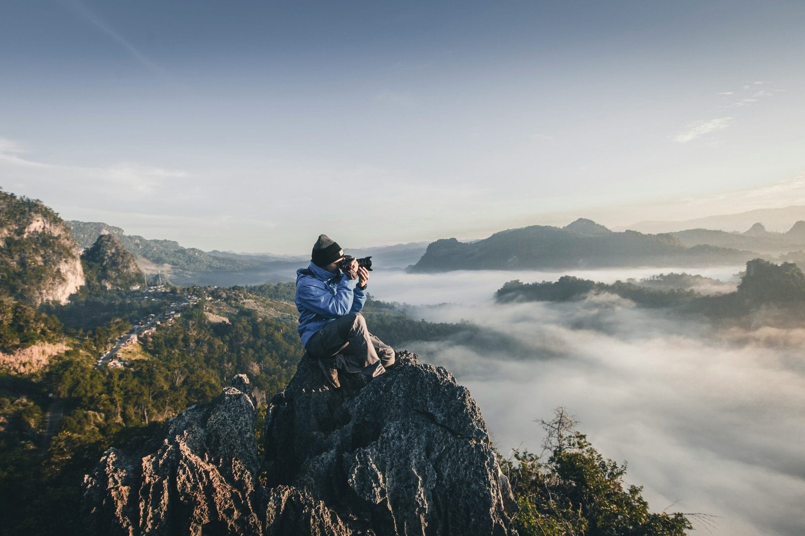Photographe au sommet d’un rocher au-dessus d’une mer de nuages