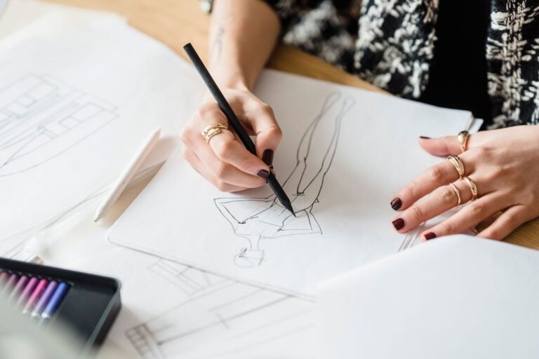 Mains baguées qui dessinent au crayon sur papier blanc